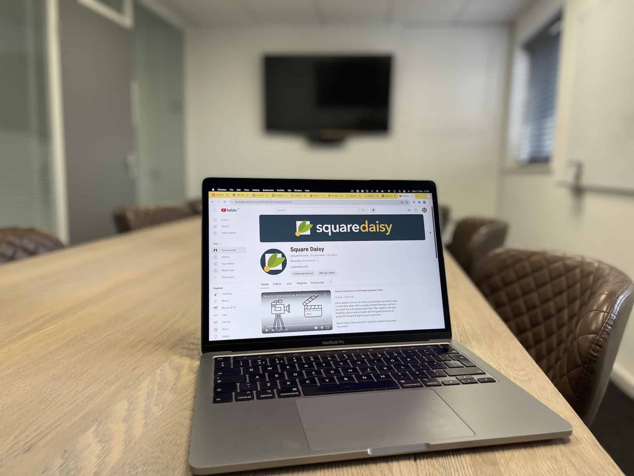 Laptop screen in the boardroom with TV screen behind, with the Square Daisy YouTube landing page on screen