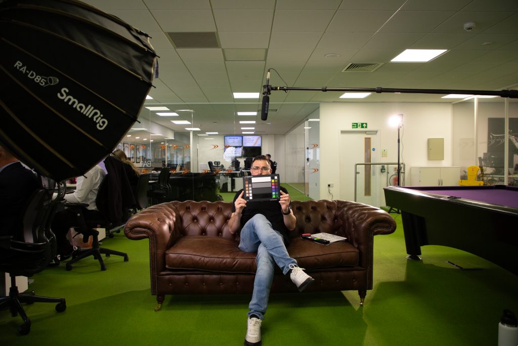 Jovan sitting with the Calibrite Colour Checker facing the camera with the colour side showing