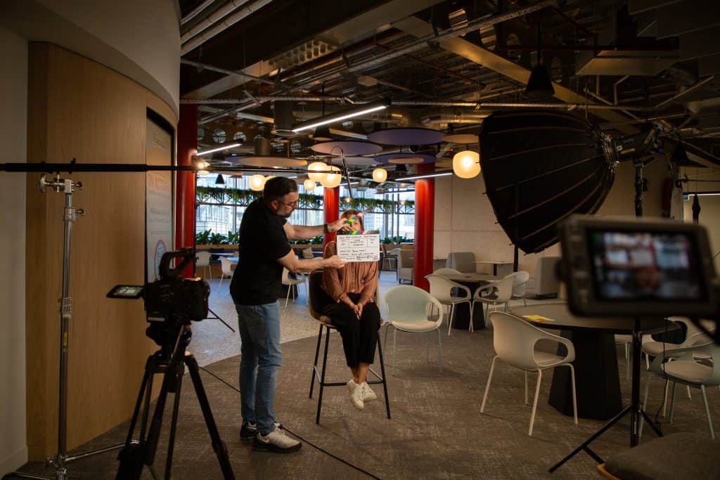 Jovan holding a clapperboard in front of the face of an interviewee
