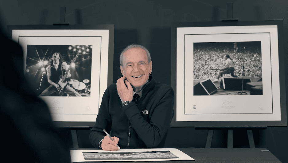 Signing session with Francis Rossi, sat at table smiling and signing